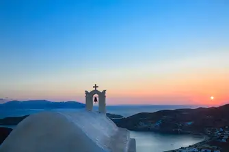 Sail by white washed buildings silhouetted on the skyline