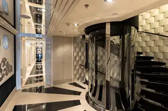 The gentle incline of the stairwell wraps around the glass elevator